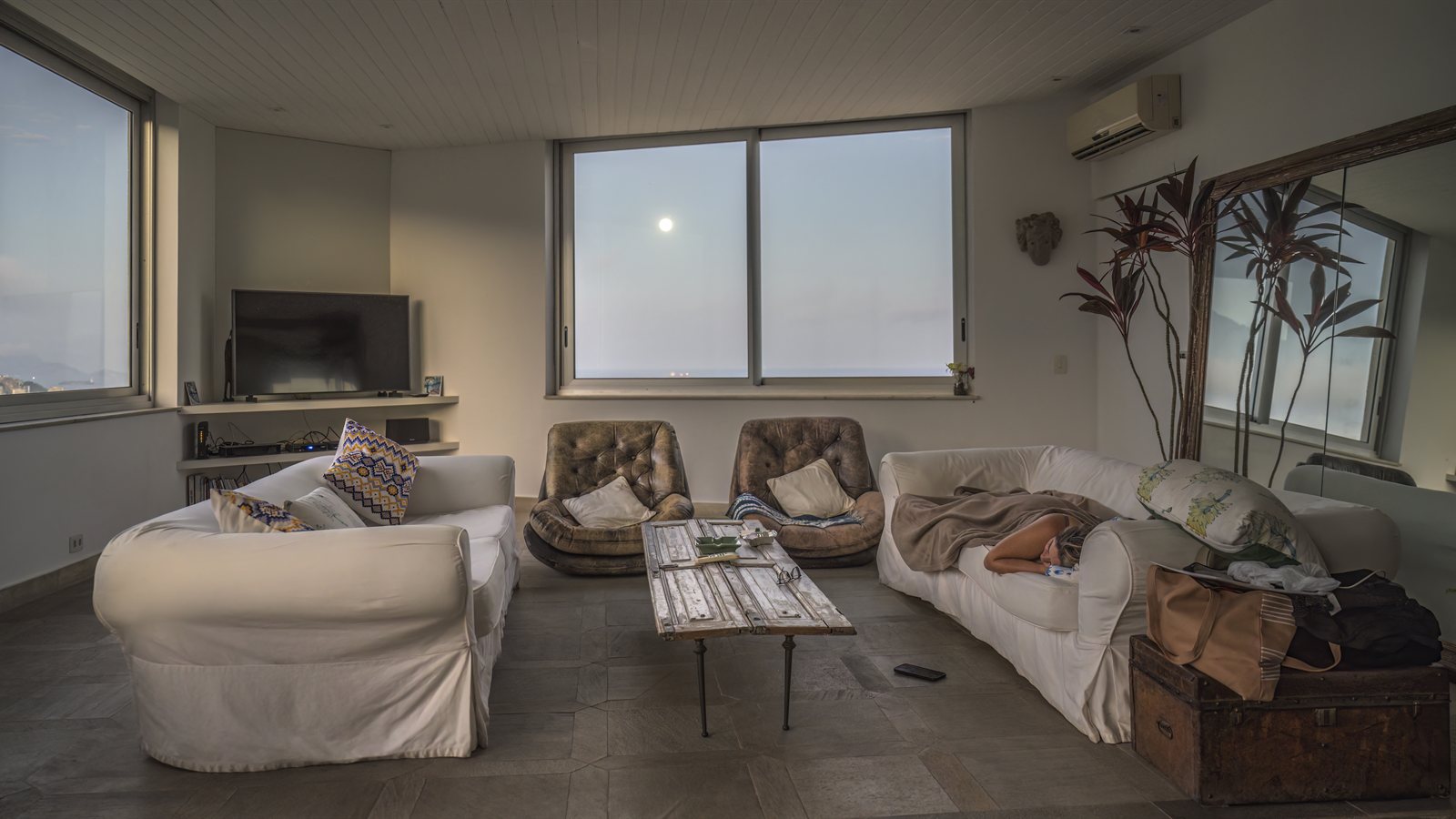 Apartment living room with wide windows at dusk