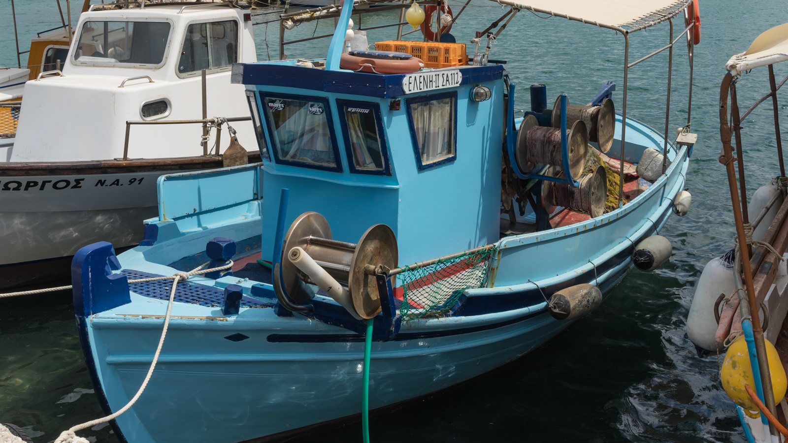 Blue fishing boat tied up in a calm harbour