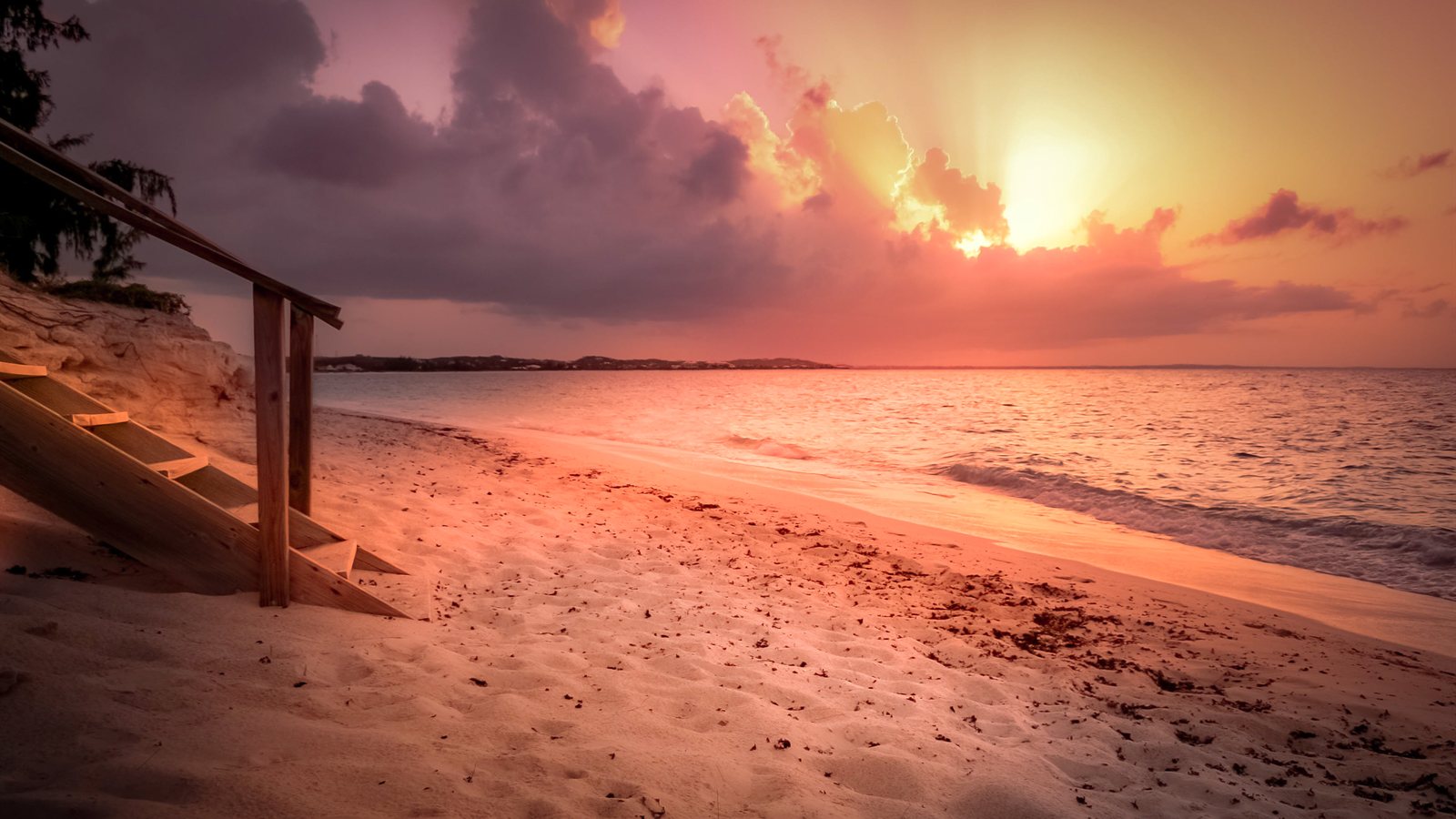 Wide sandy beach glowing under a pink and gold sunset