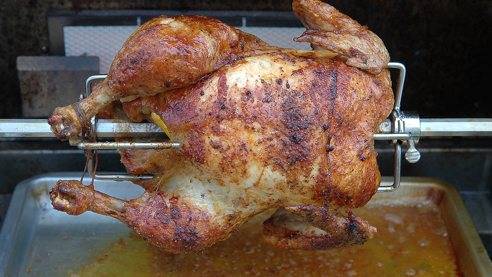 Whole chicken turning on a rotisserie spit