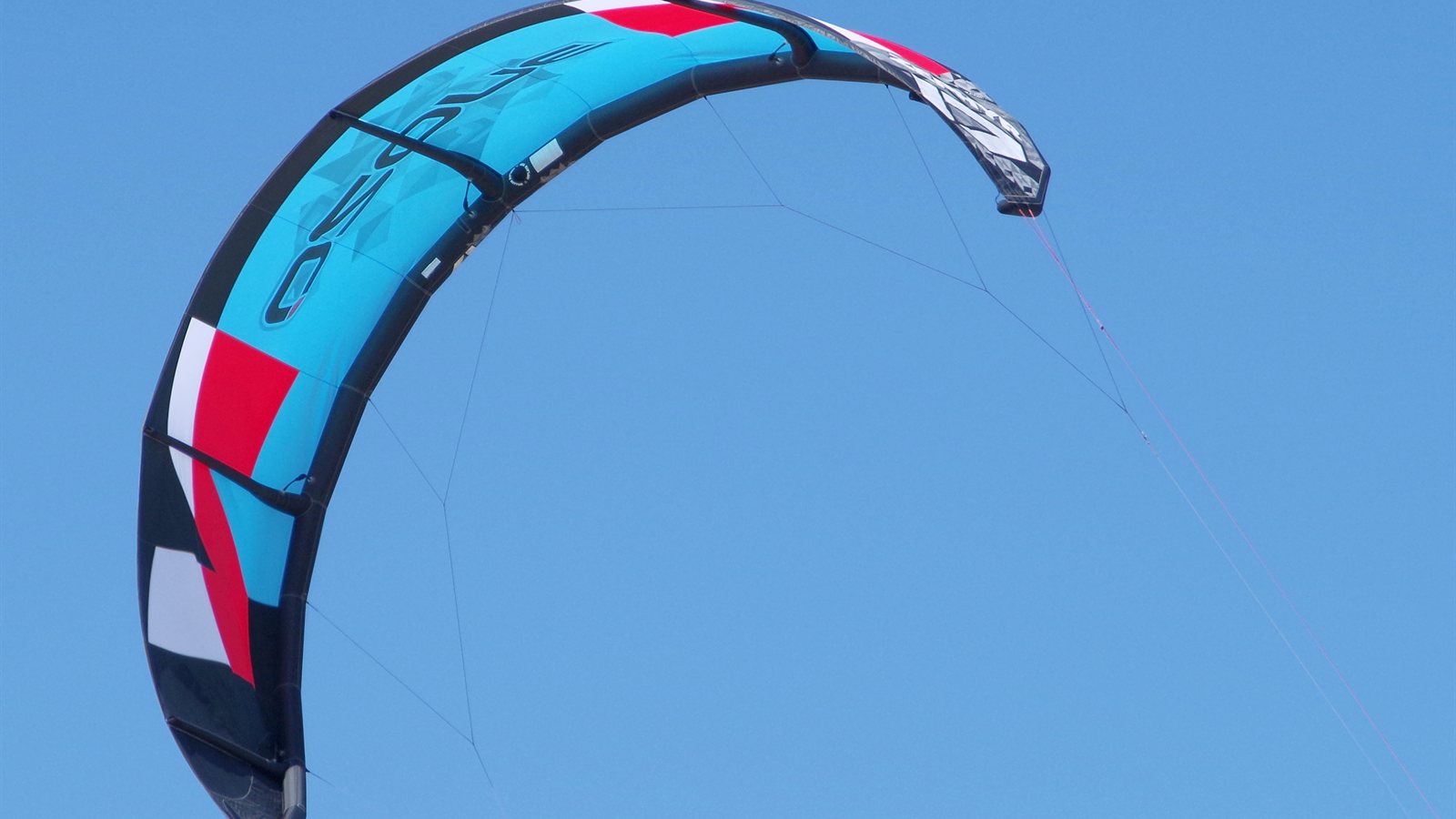 Kite arcing against a clear blue sky