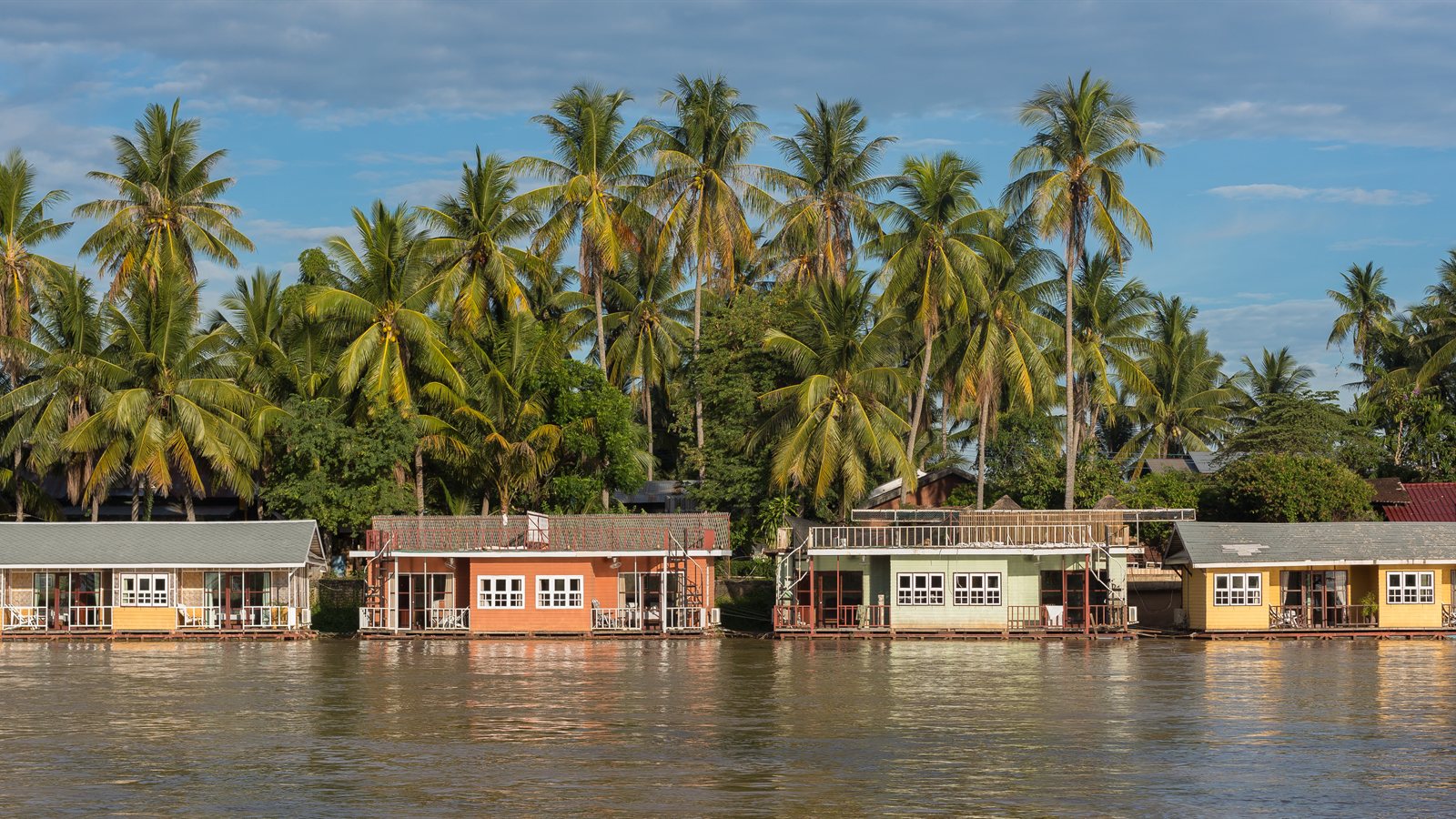 Brightly painted floating bungalows moored along a channel