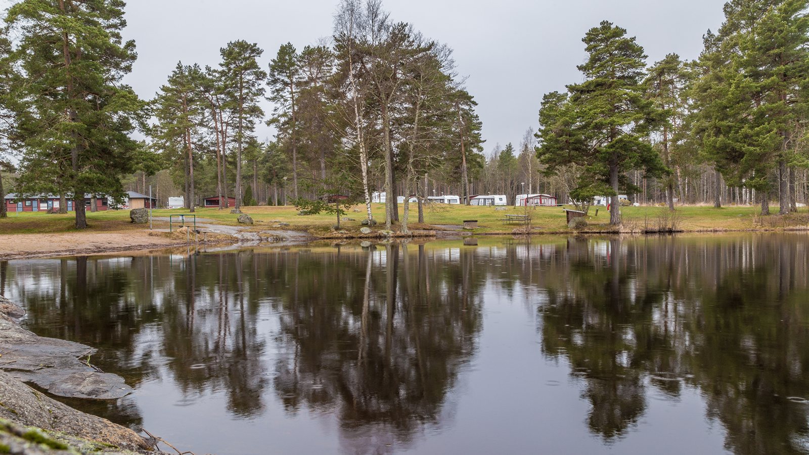 Quiet campsite among pines reflected in still water
