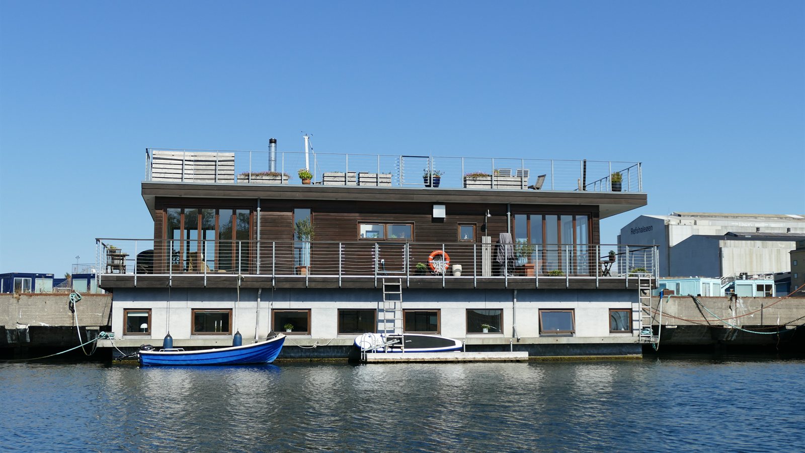 Dark-clad houseboat moored along a city quay