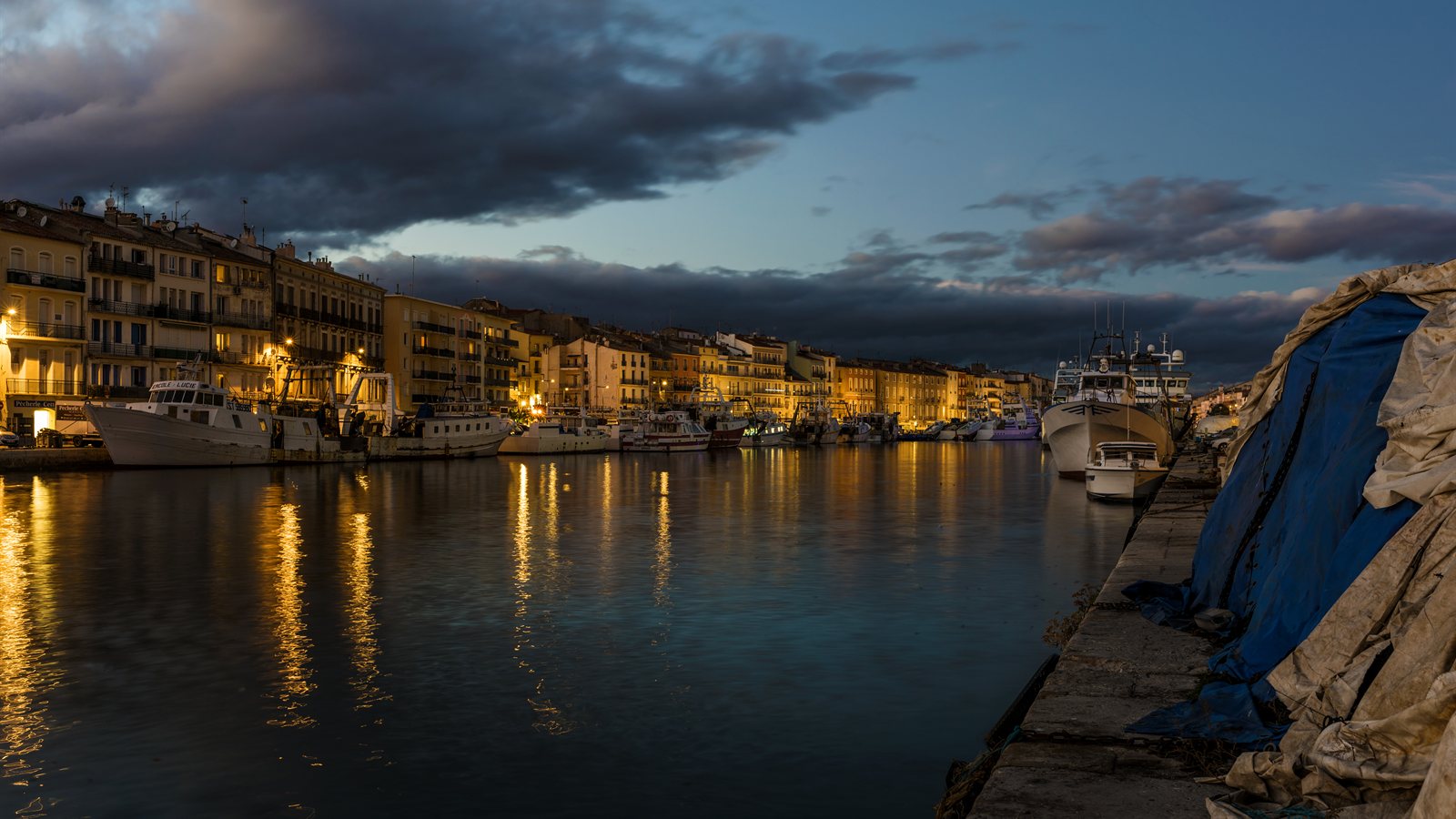 Canal lined with moored boats at dusk