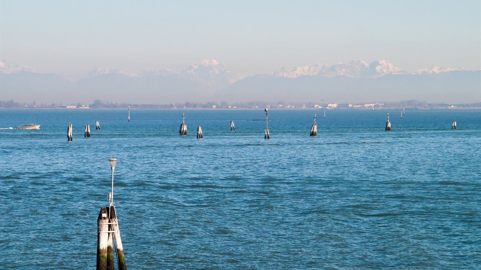 Lagoon water with wooden channel markers and distant mountains