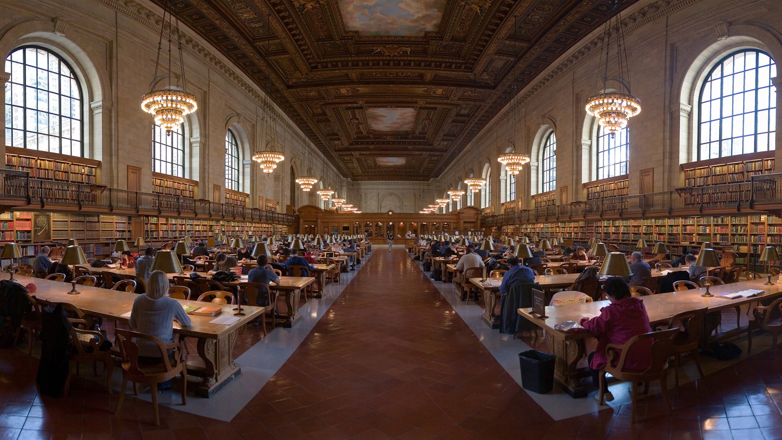 Grand reading room with long desks and lamps
