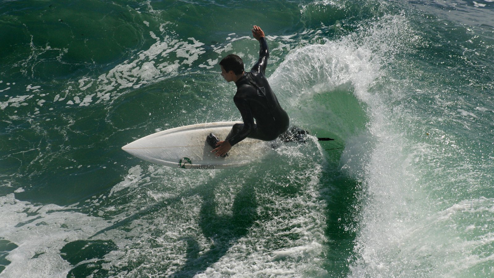 Surfer turning off the top of a green wave