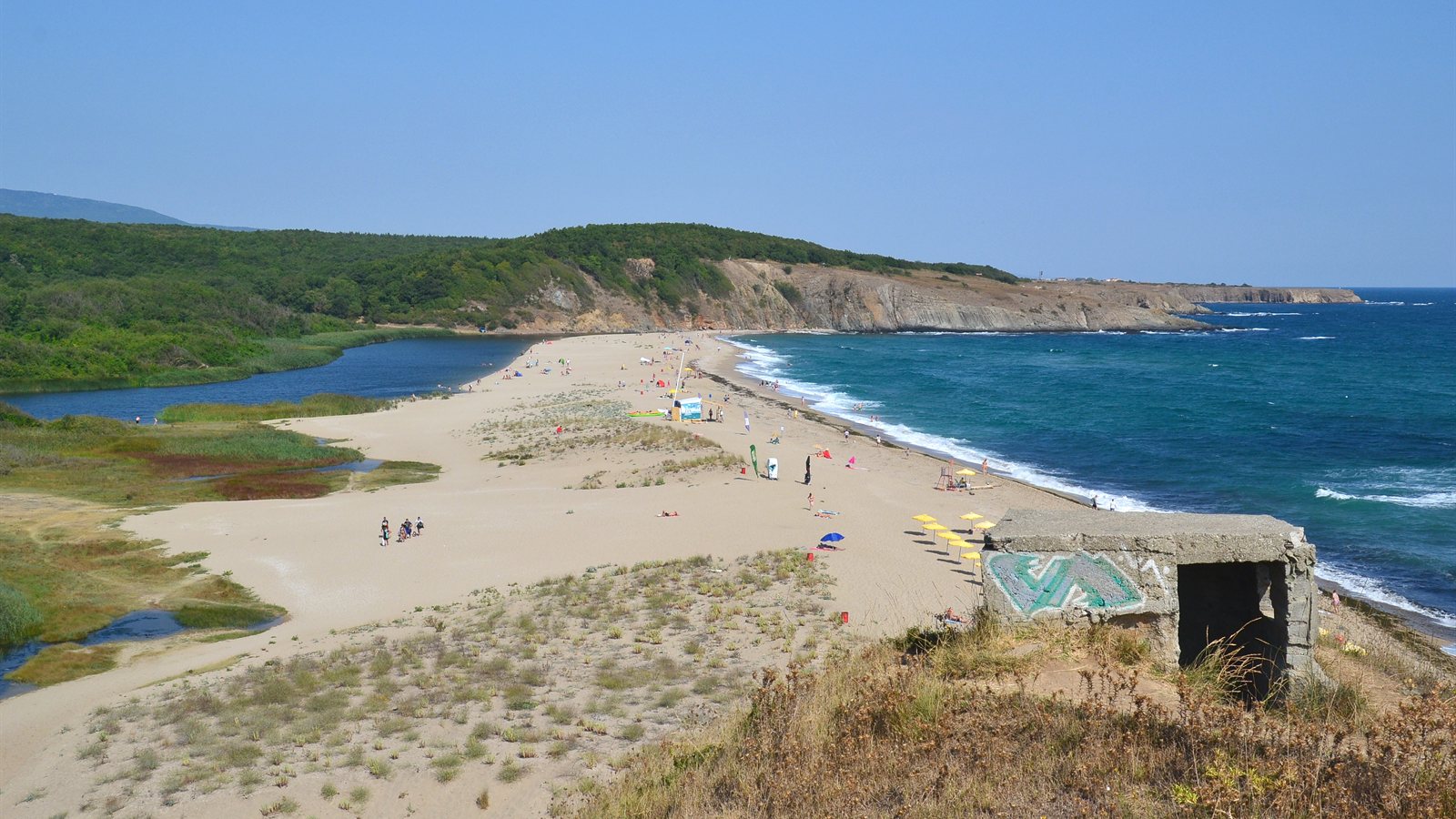 River winding across the sand into the sea beside a beach