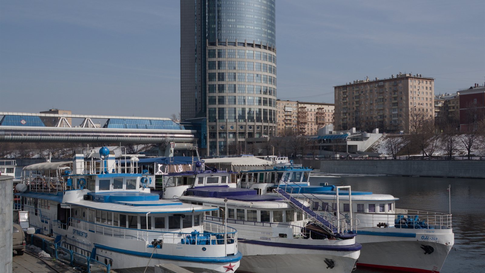 City river with moored vessels beside a modern bridge