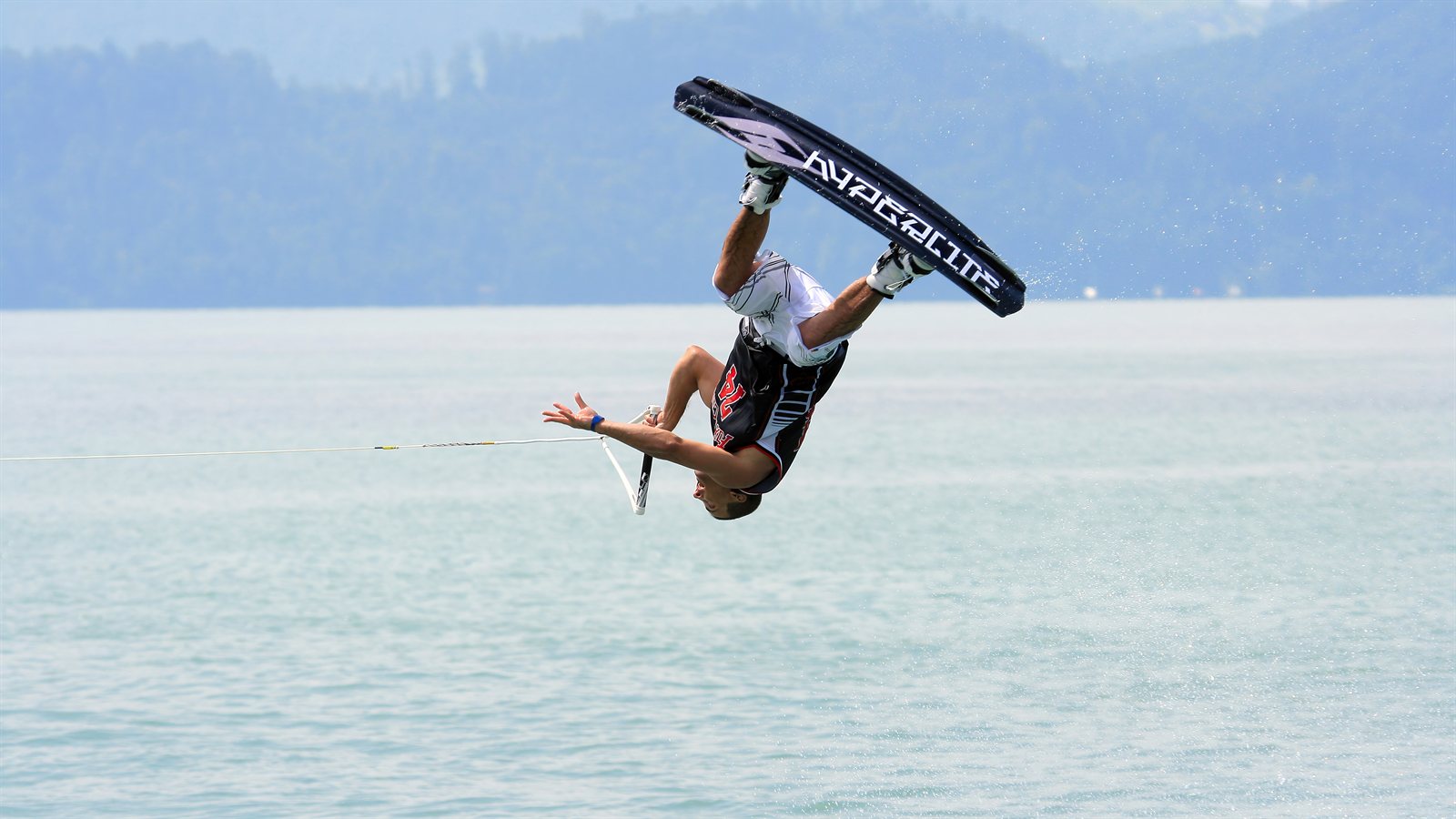 Wakeboarder inverted mid-air above open water