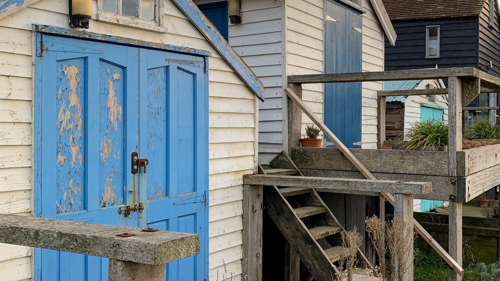 Weathered wooden beach huts with blue doors above the sand