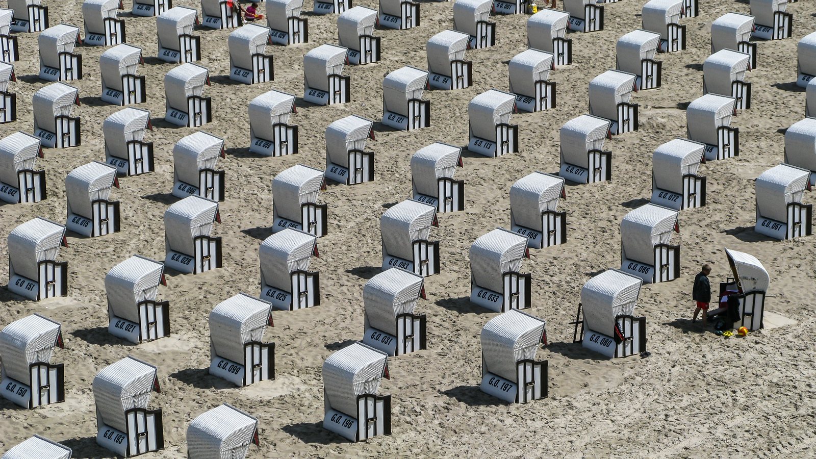 Rows of hooded wicker beach chairs facing the sea