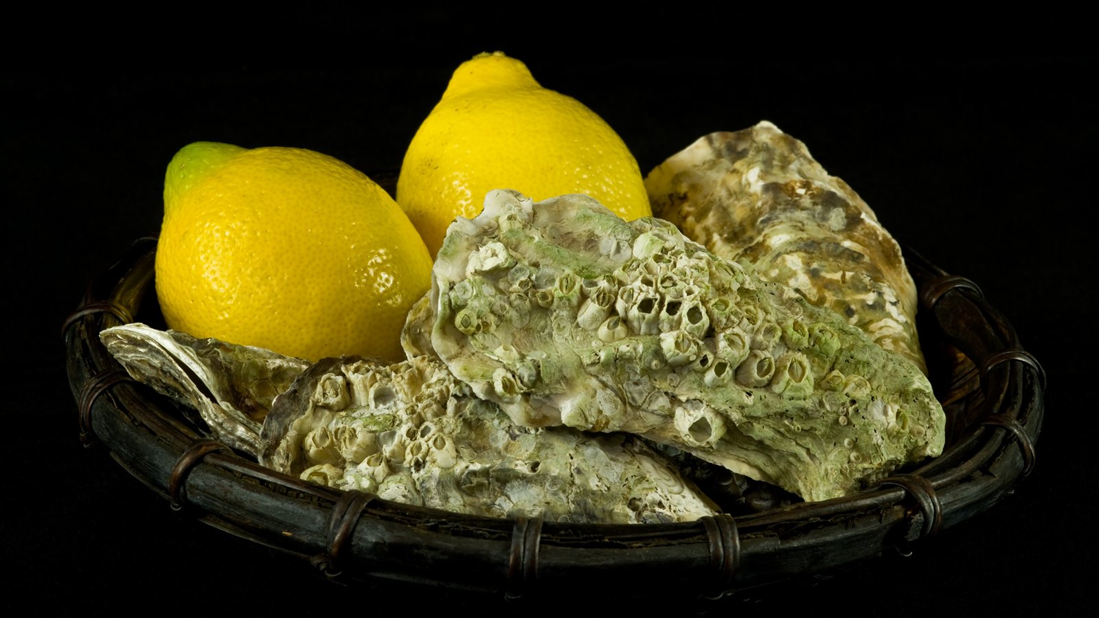 Oysters and lemons arranged in a woven basket