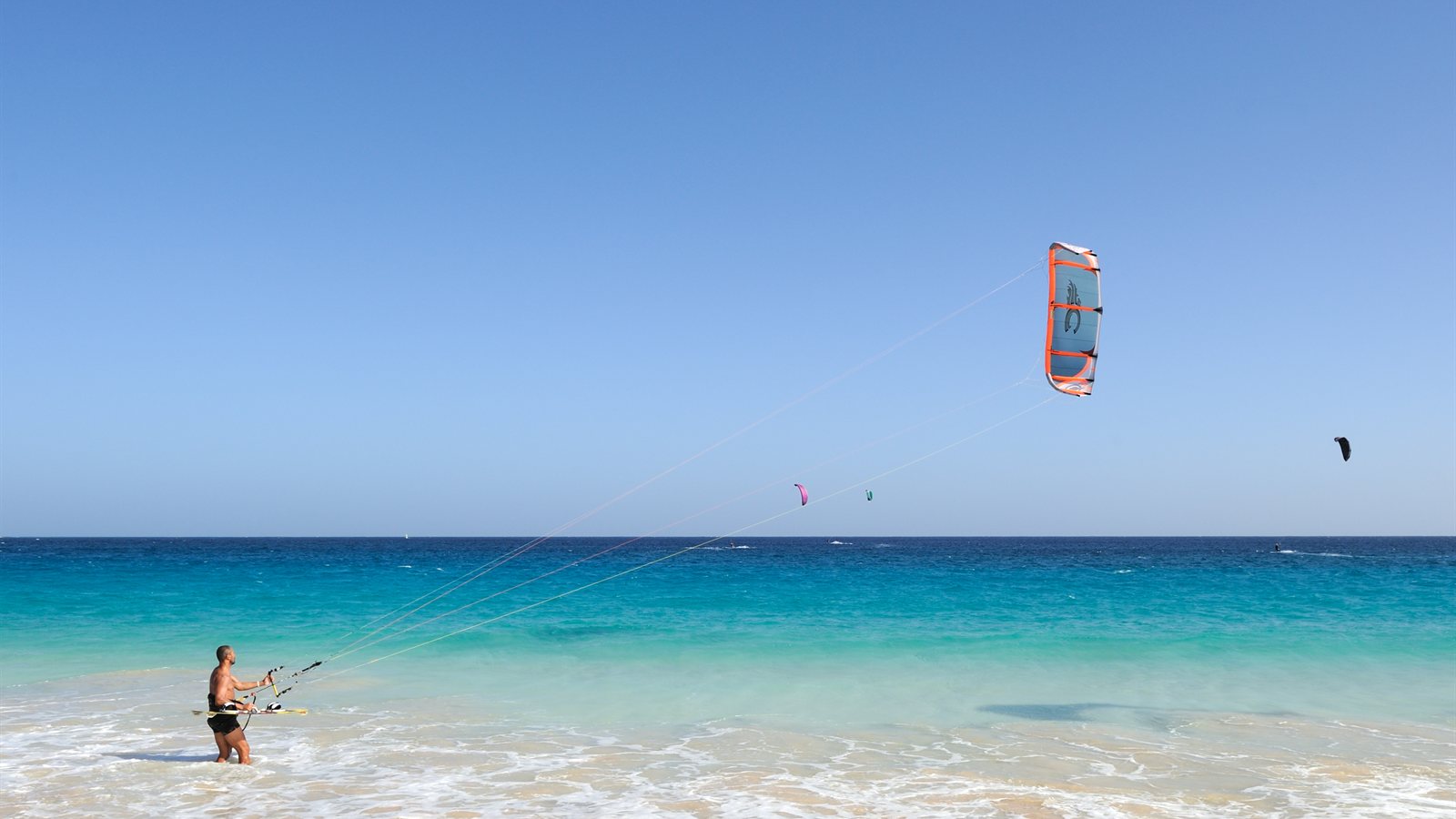 Beginner controlling a kite from waist-deep turquoise shallows
