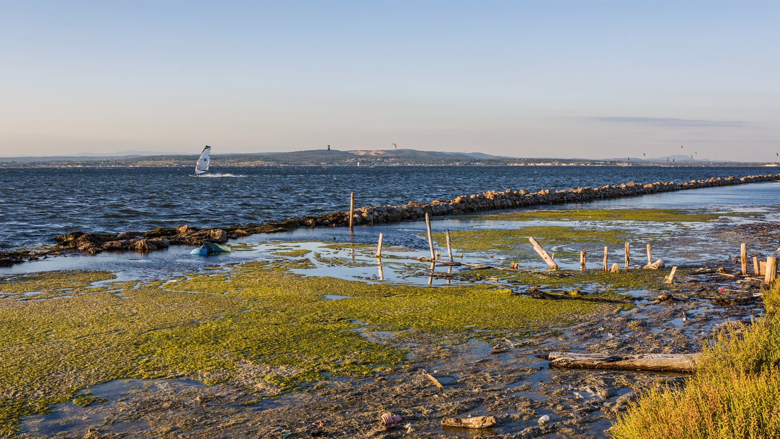 Windsurfer crossing a shallow lagoon in evening light