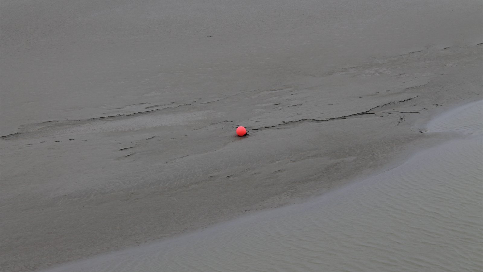 Ribbed tidal sand flat with a single red marker buoy