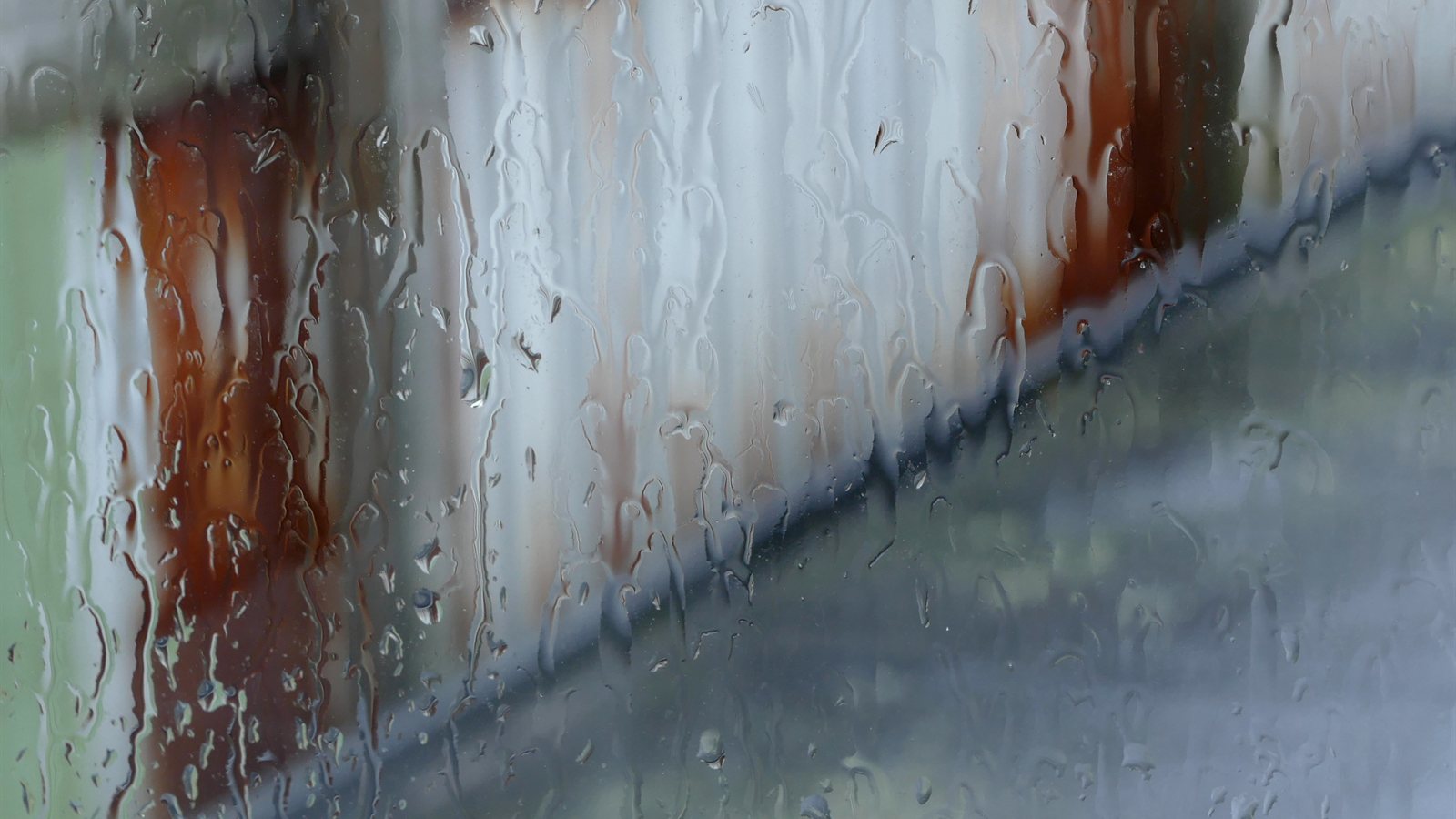 Rain streaming down a window over a blurred harbour view