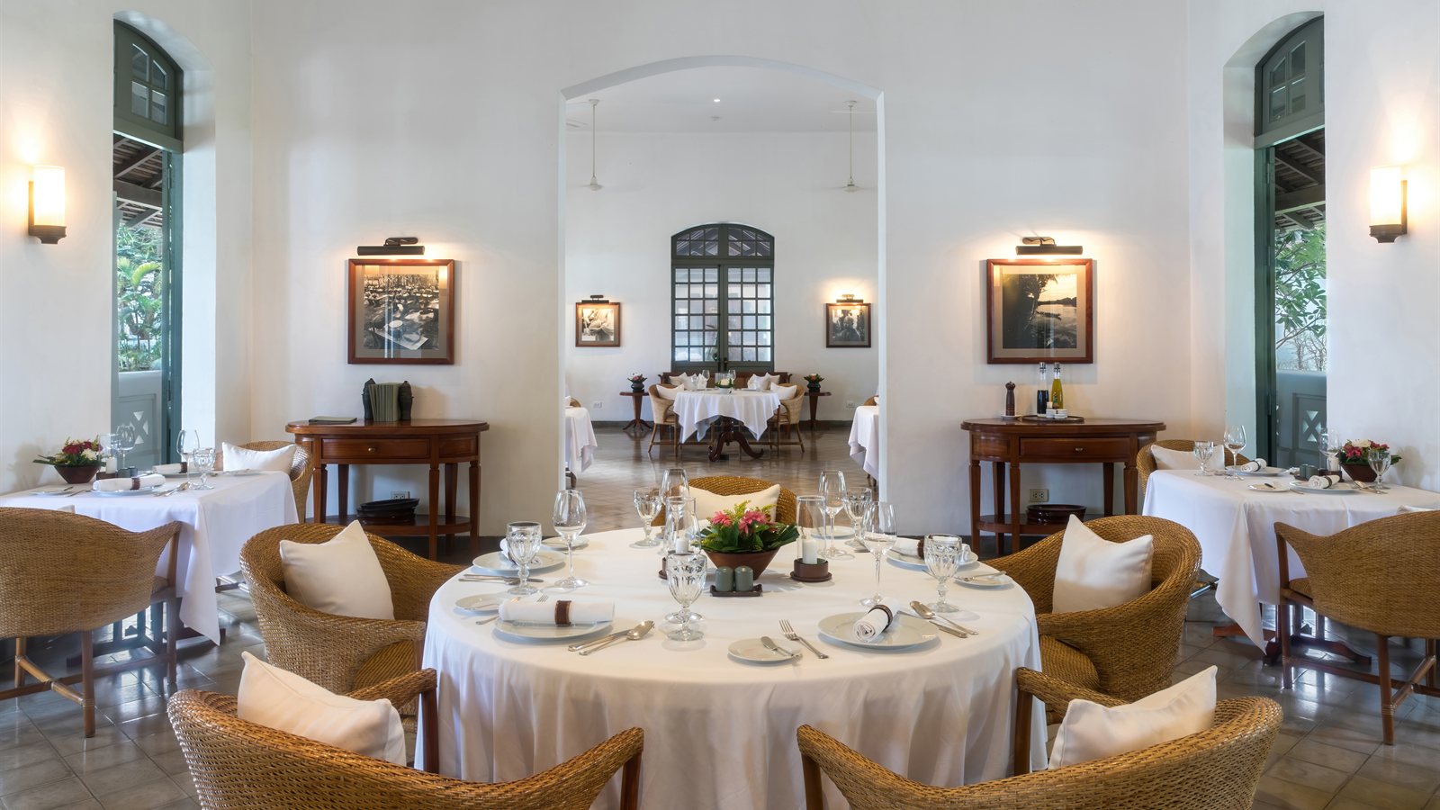 Dining room with white walls, tall shutters and set tables