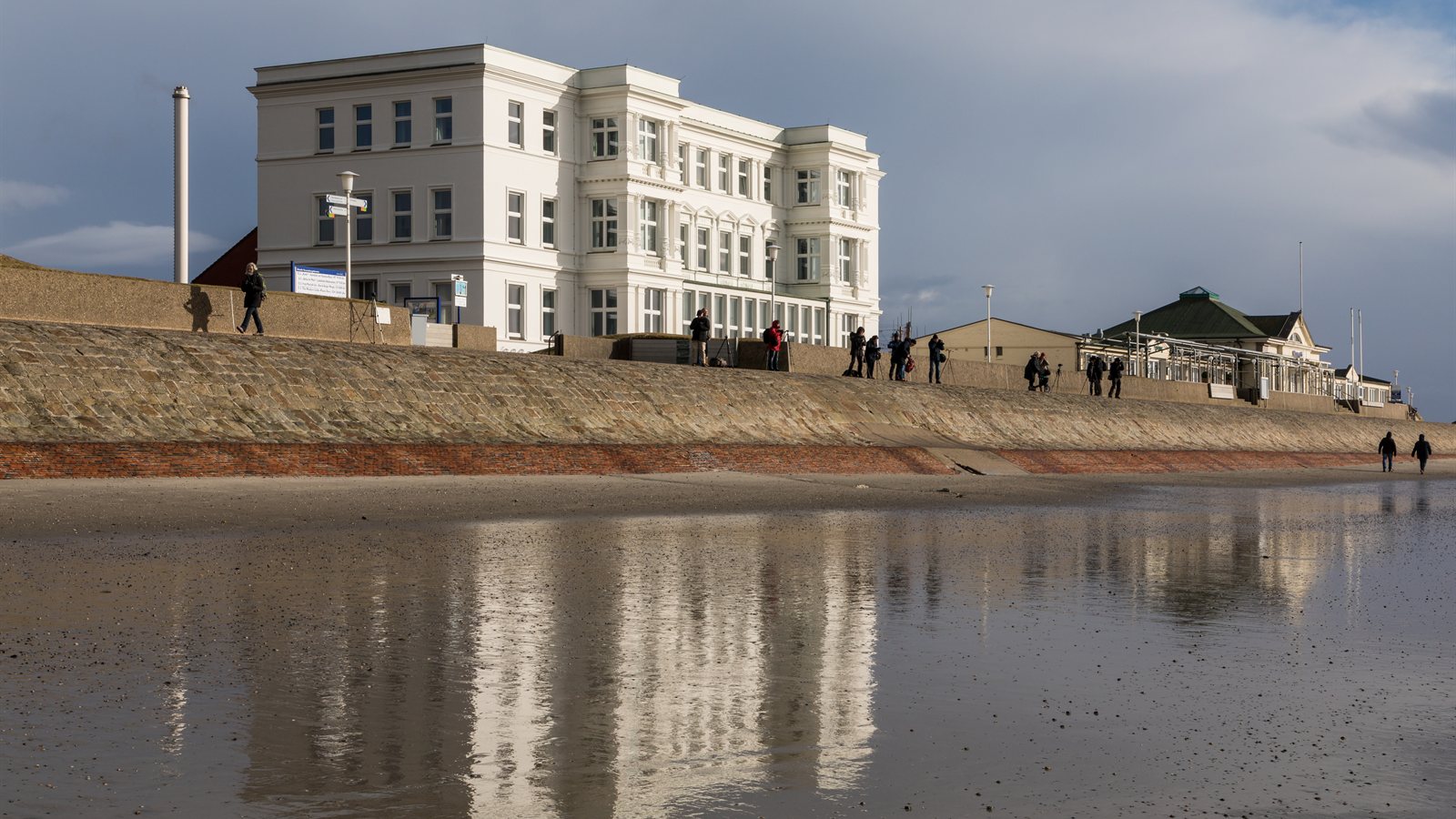 White resort building above a seafront promenade at low tide