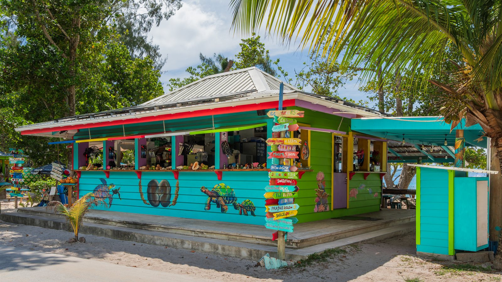 Colourful wooden beach bar shaded by palms