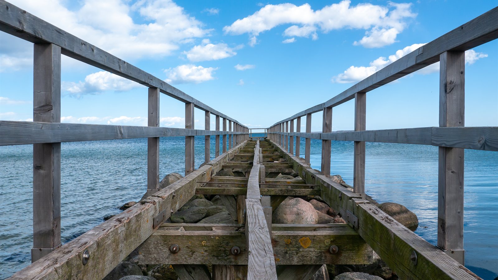 Long wooden pier stretching out over calm blue water