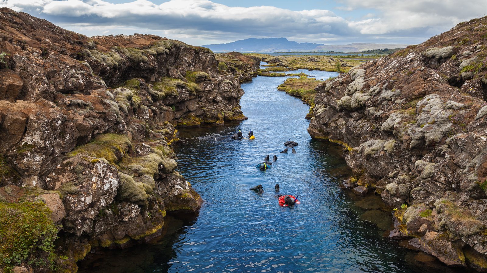 Diver in exceptionally clear cold water between rock walls