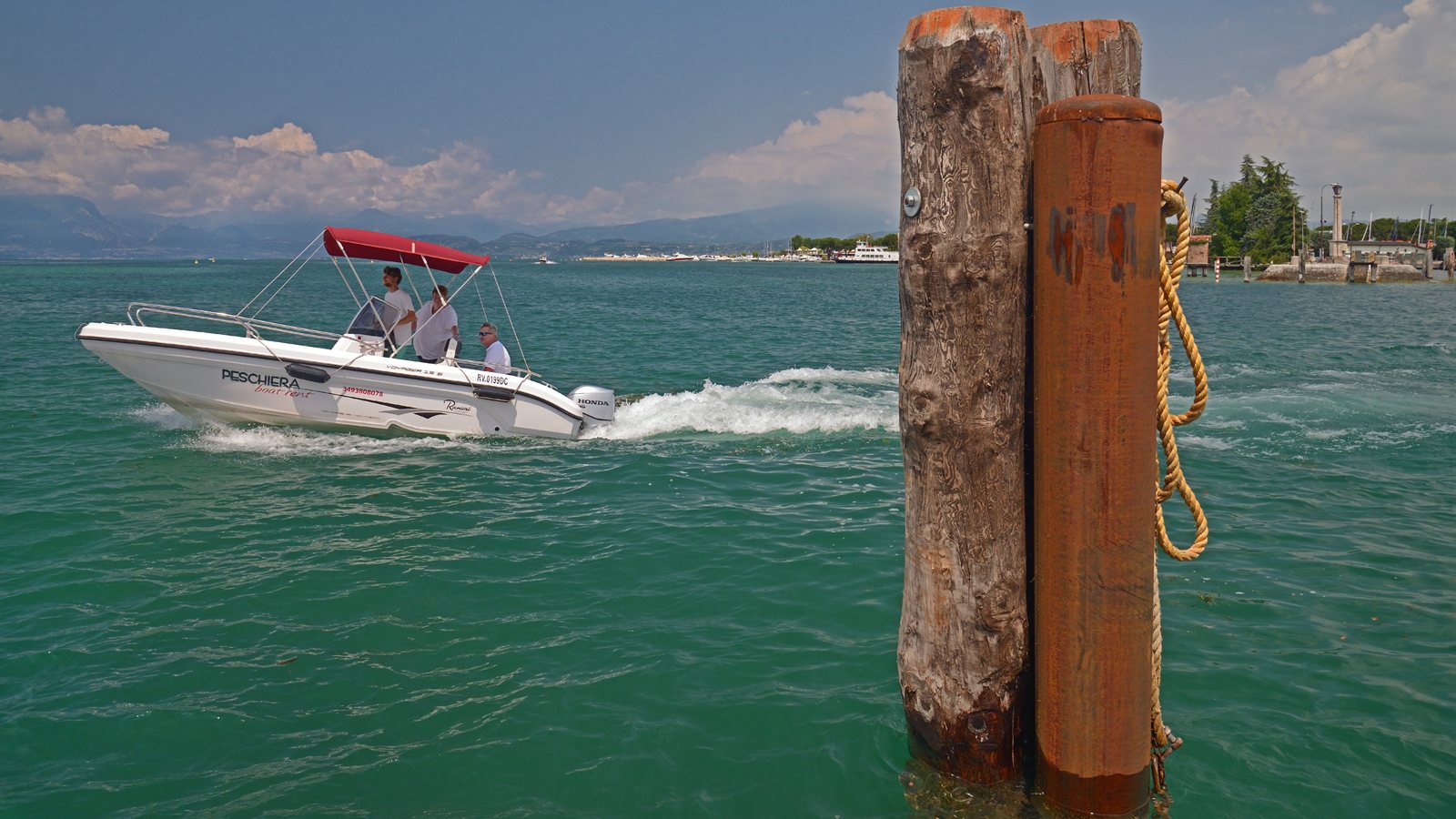Small motorboat passing wooden mooring poles on a lake